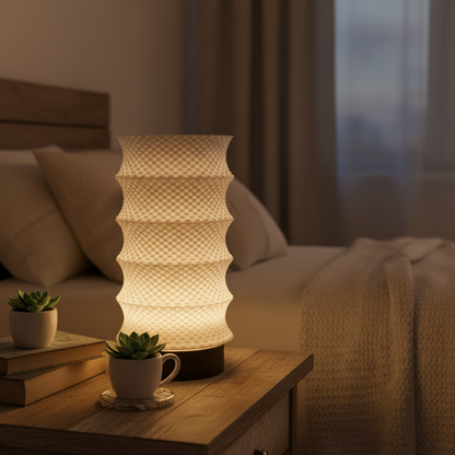 Decorative lamp on a bedside table with books and a plant in a cozy bedroom setting.