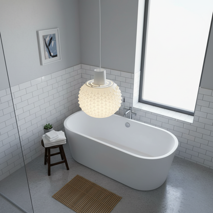 White sculptural pendant light centered above a freestanding bathtub in a minimalist bathroom.