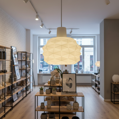 White geometric pendant lamp displayed in a modern interior showroom with wooden shelves and home decor.