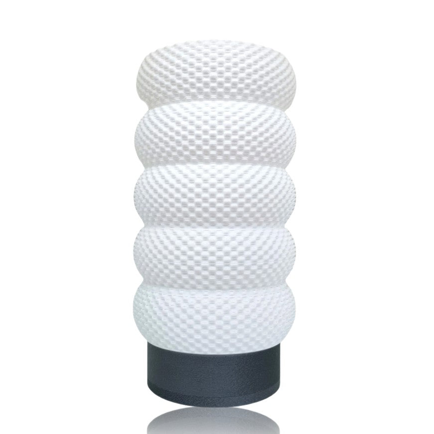 White textured cylindrical table lamp with a black base on a white background