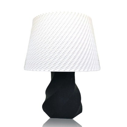 Table lamp with a black base and white textured shade on a white background