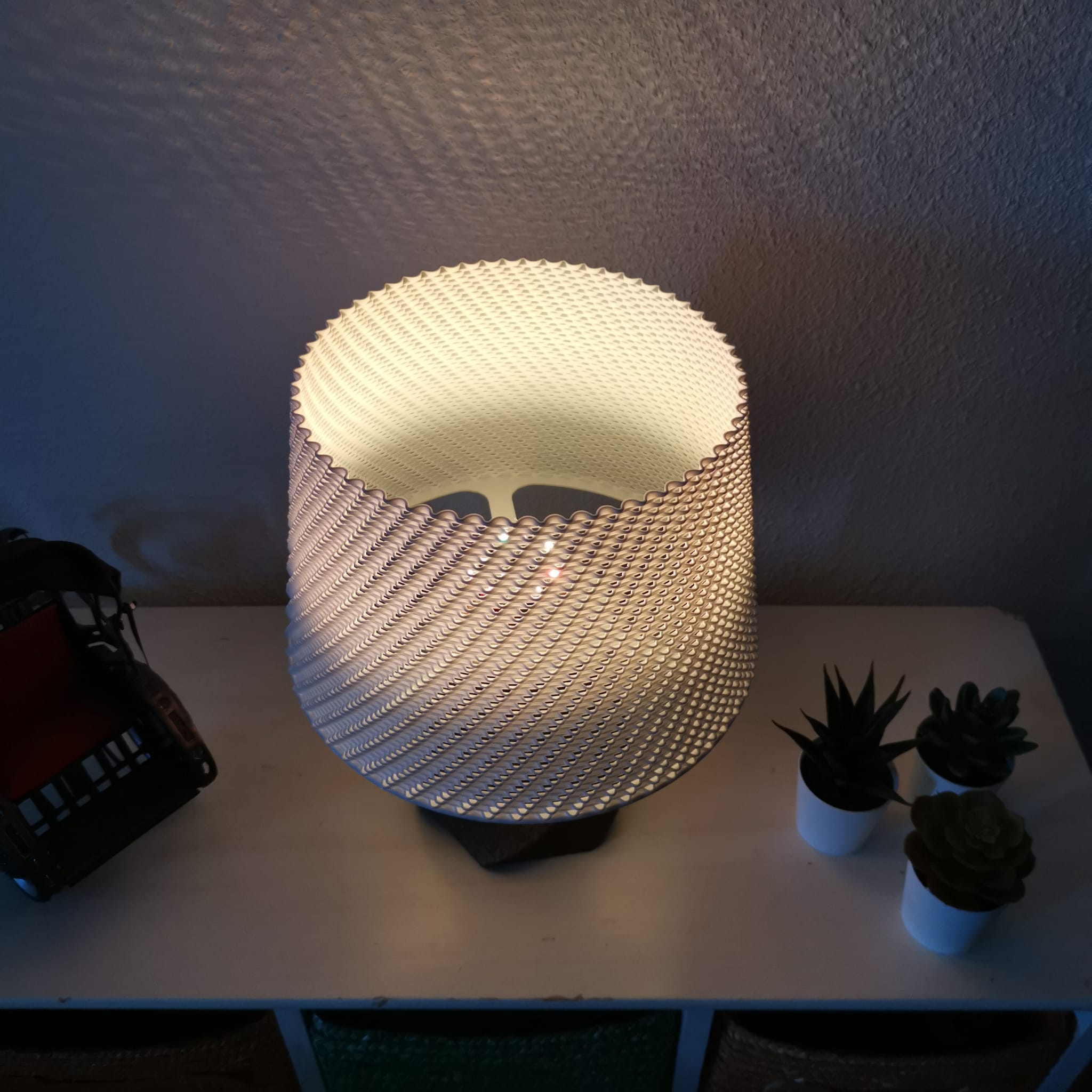 Textured table lamp on a surface with plants in the background