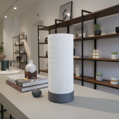 White textured cylindrical lamp on a table with a blurred background of shelves and decor items.