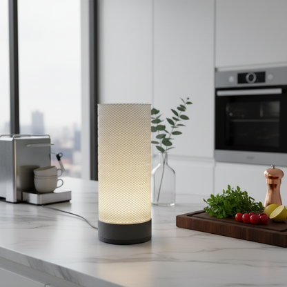 Modern kitchen with a lit table lamp on a countertop, coffee machine, and cutting board with vegetables.