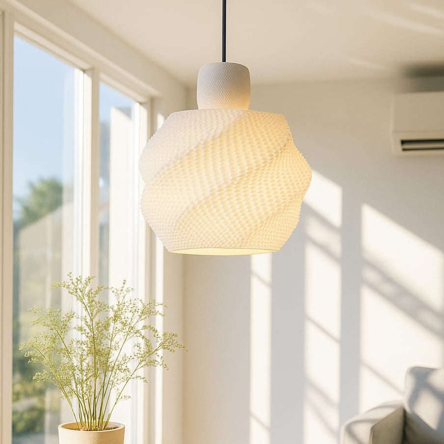Modern pendant light hanging in a bright room with a plant on a table and a sofa.